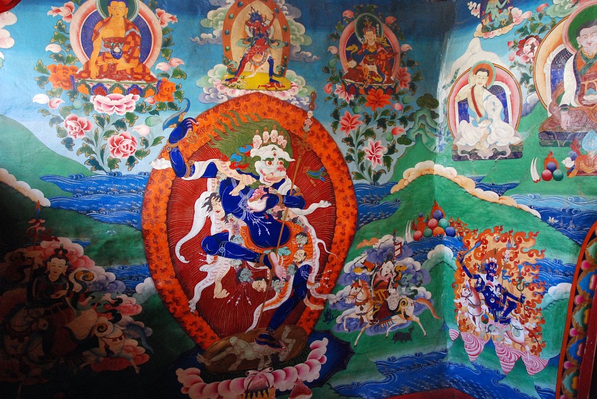 33 Paintings Outside Cave Of The Female Yak Horns Dirapuk Gompa Lion-Faced Goddess Dakini Simhamukha Senge Dongma, Padmasambhava Guru Rinpoche, Milarepa, Marpa, Shangpa Karpo, Shri Devi Palden Lhamo At the back of the Dirapuk Gompa is the cave of the female yak horns. Murals surround the entrance including the lion-faced-goddess Dakini Simhamukha (Tib. Senge Dongma). The face is a white lion with three round orange eyes blazing fiercely with a gaping mouth, and hair flowing upward. The right hand holds upraised a curved knife to the sky, left a skullcup of blood to the heart, carrying a khatvanga staff tipped with a trident in the bend of the elbow supported against the shoulder. Above to the left is Buddha, then Chakrasamvara (Tib. Demchog) in yab-yum with Vajrayogini (Tib. Dorje Phagmo), Padmasambhava (Tib. Guru Rinpoche), Milarepa holding his hand to his ear, Milarepa�s teacher Marpa, At the lower left is the worldly protector Shangpa Karpo, white, with one face and two hands holding a lance in the right and a bowl of jewels in the left; riding a white horse. I�m not sure who the figure is to the right of lion-faced goddess. He is white with one face and two hands holding upraised in the right a riding whip and in the left a spear with a red banner. The final figure to the lower right is Shri Devi (Tib. Palden Lhamo), dark blue in colour, riding side saddle on a white mule with a sword in her upper right, a skullcup in her lower right, and khatvanga in her first right hand and another staff in her far right hand. She has a sun and moon disc at her waist.